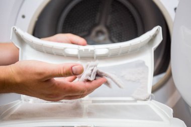 Kurutucu filtre, kirli ve temizlenmesi gerekiyor. Çamaşır tozu bir yerde toplanmış.