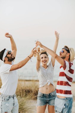 Üç genç arkadaş sahilde bira ile kutluyor