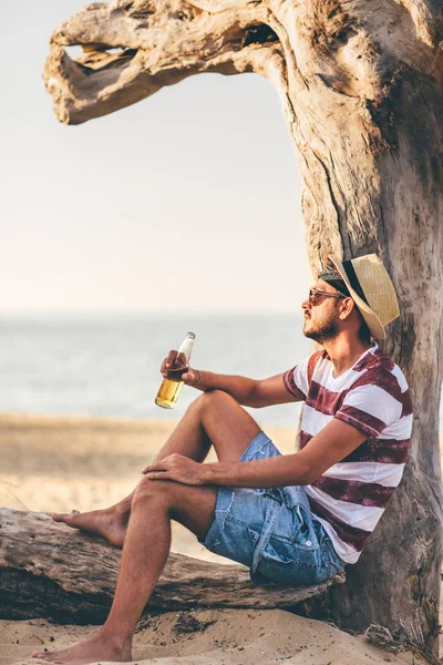 Jovem Sentado Perto Árvore Seca Bebendo Cerveja Litoral — Fotografia de Stock