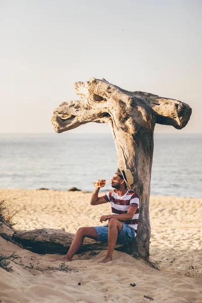 Joven Sentado Cerca Del Árbol Seco Bebiendo Cerveza Costa — Foto de Stock