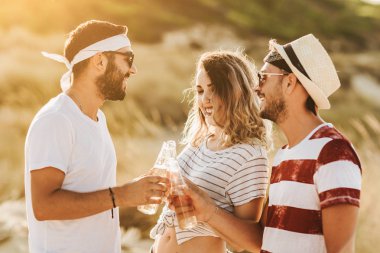 Konuşmak ve bira içmek sahilde mutlu gençlerin Grup