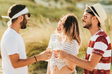 Konuşmak ve bira içmek sahilde mutlu gençlerin Grup