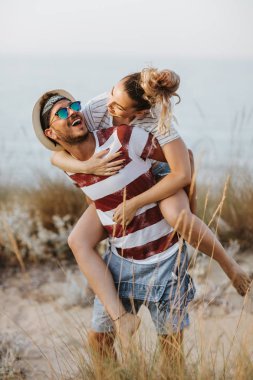 Kız arkadaşı deniz kıyısında sırtında taşıyan adam portresi. Sırtıma binmek sahilde kız arkadaşına veren adam.