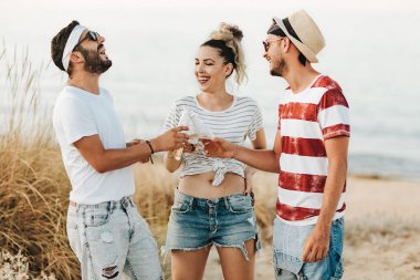 Konuşmak ve bira içmek sahilde mutlu gençlerin Grup