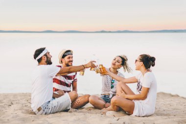 Gençlerin grup birlikte konuşmak ve bira içmek sahilde oturup mutlu