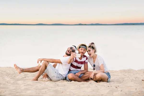Grupo Jóvenes Felices Sentados Juntos Playa Tomando Selfie —  Fotos de Stock