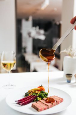 ve pancar ve yeşillik ile gurme sığır bifteği üzerinde sos dökme kişi tutan kırpılmış shot