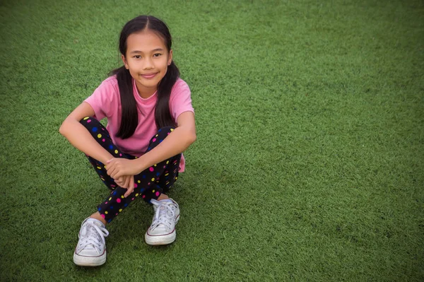 Asiático Chica Siting Sonrisa Mirando Artificial Hierba Campo Fondo — Foto de Stock