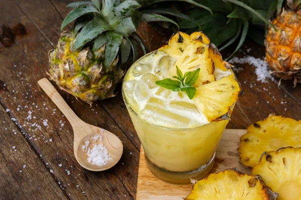 Pineapple juice and pineapple slices cut into pieces on a wooden