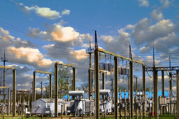 High voltage electric power station - electric poles and lines on blue sky with vanilla clouds background