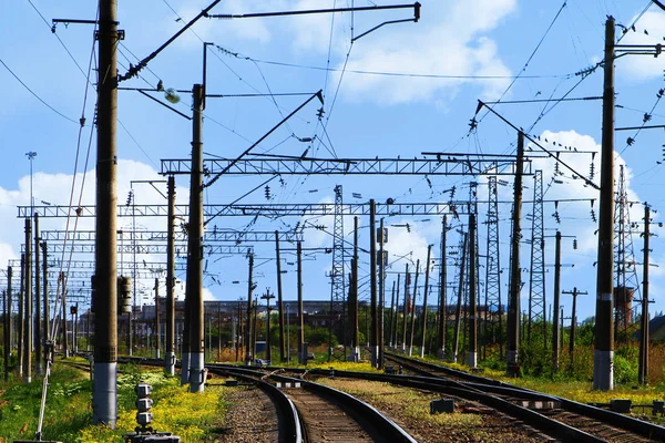 Railroad crossing at station with electric poles on the blue sky background
