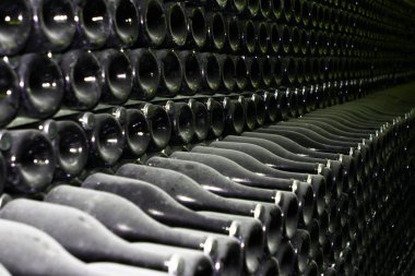 Şarap mahzeninde yığılmış birçok eski şampanya şişeleri yakın çekim