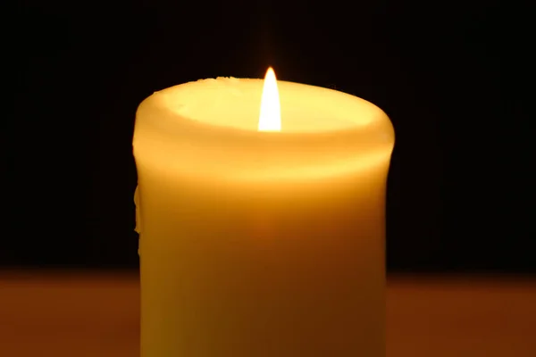 黒の背景に明るい炎が付いている蝋燭を燃やす小さなワックス — ストック写真