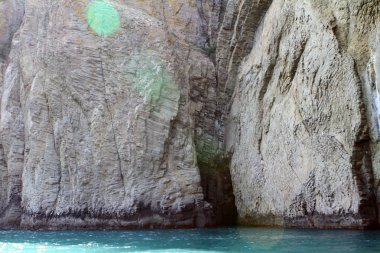 Doğal peyzaj fotoğraf - mağara girişi deniz yüzeyinde bir dağ yamacında.