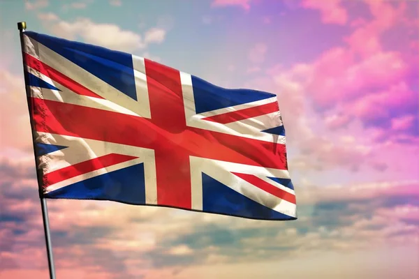 Fluttering United Kingdom (UK) flag on colorful cloudy sky background. United Kingdom (UK) prospering concept.