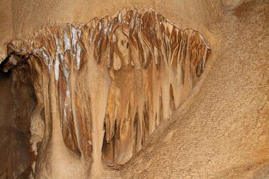 fantastic natural cave with fulvous walls and formations of stalagmites and stalactites in it, natural texture photo. clipart