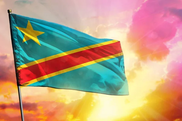 Fluttering Democratic Republic of Congo flag on beautiful colorful sunset or sunrise background. Democratic Republic of Congo success or happiness concept.