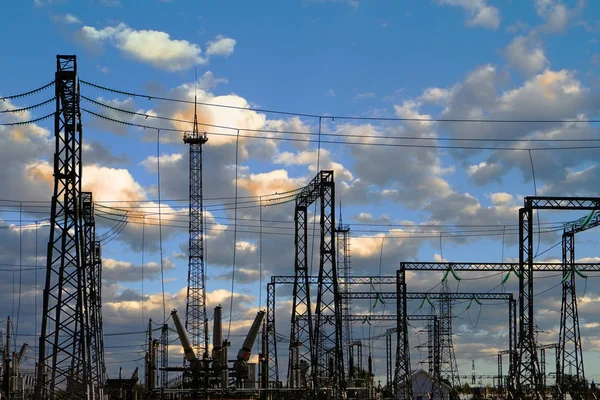 High voltage electric power station - electric poles and lines on blue sky with clouds background