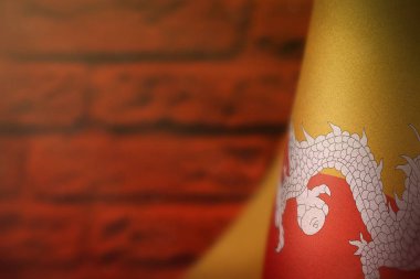 Bhutan bayrağı onur Gaziler günü veya anma günü için kırmızı üzerinde asılı boyalı tuğla duvar arka plan bulanık. Bhutan zafer için savaş kavramı kahramanları.