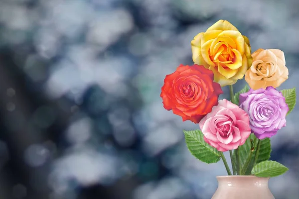 Beautiful live rose bouquet bouquet in porcelain vase on sunny day with empty space for your content on park trees and sky blurred background.