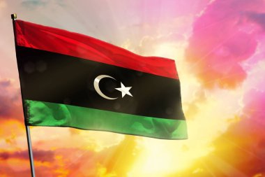 Libya bayrağı güzel renkli günbatımı veya gündoğumu arka planda çırpınan. Başarı kavramı.