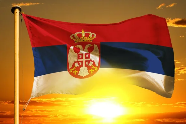 Flaga Serbii tkania na piękny pomarańczowy zachód słońca z tle chmury — Zdjęcie stockowe
