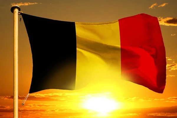 Bandera de Bélgica tejiendo en la hermosa puesta de sol naranja con las nubes de fondo — Foto de Stock