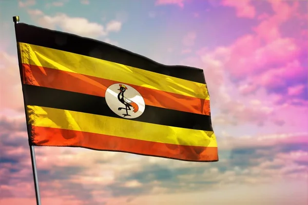 Fluttering Uganda vlag op kleurrijke bewolkte hemel achtergrond. Welvaart concept. — Stockfoto