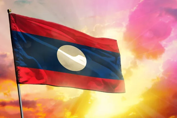 Ondeando la bandera de la República Democrática Popular Lao sobre un hermoso fondo colorido al atardecer o al amanecer. Concepto de éxito . — Foto de Stock