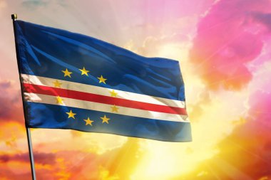 Güzel renkli günbatımı veya gündoğumu arka plan üzerinde Fluttering Cabo Verde bayrağı. Başarı kavramı.