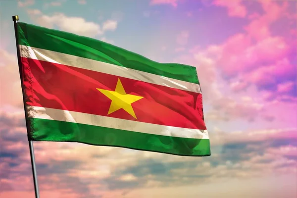 Ondeando la bandera de Surinam sobre el colorido fondo nublado del cielo. Concepto de prosperidad . — Foto de Stock