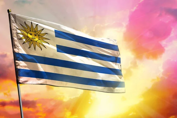Fluttering σημαία της Ουρουγουάης σε όμορφο πολύχρωμο ηλιοβασίλεμα ή την ανατολή του ηλίου φόντο. Έννοια επιτυχίας. — Φωτογραφία Αρχείου