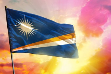 Güzel renkli günbatımı ya da gündoğumu arka planında dalgalanan Marshall Adaları bayrağı. Başarı konsepti.