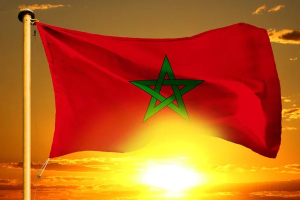 Morocco flag weaving on the beautiful orange sunset with clouds background — Stock Photo, Image