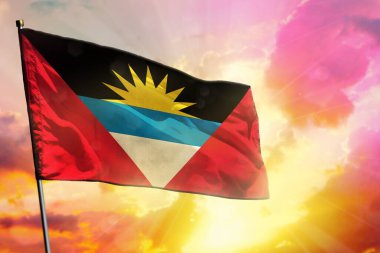 Renkli günbatımı ya da gündoğumu arka planında dalgalanan Antigua ve Barbuda bayrağı. Antigua ve Barbuda başarı ve mutluluk kavramı.
