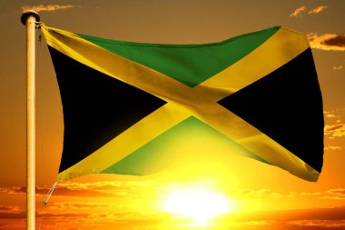 Güzel turuncu günbatımı arka planında Jamaika bayrağı sallanıyor