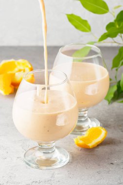İki kokteyl cam ile smoothies milkshake sağlıklı içecek portakal narenciye peel muz süt yoğurt ve dondurma hareket sürahi damla sağlıklı beslenme elma püresi