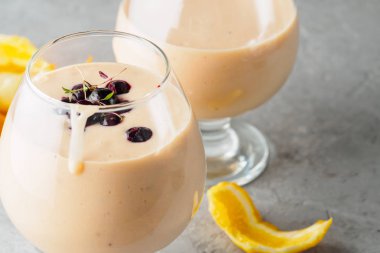 İki kokteyl cam ile smoothies milkshake sağlıklı içecek portakal narenciye peel muz süt yoğurt ve dondurma siyah frenk üzümü sağlıklı diyet yiyecek çilek ile