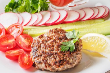 Kıyılmış biftek pirzola turp kiraz domates dilim salatalık maydanoz limon ve sosu ketçap kavramı gıda yaz ev yapımı piknik Barbekü assorty karışımı sebze ile beyaz tabakta ızgarada pişmiş