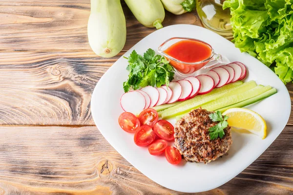 Kıyılmış biftek pirzola turp kiraz domates dilim salatalık maydanoz limon ve sosu ketçap kavramı gıda yaz ev yapımı piknik Barbekü assorty karışımı sebze ile beyaz tabakta ızgarada pişmiş