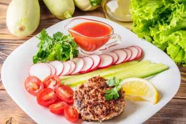 Kıyılmış biftek pirzola turp kiraz domates dilim salatalık maydanoz limon ve sosu ketçap kavramı gıda yaz ev yapımı piknik Barbekü assorty karışımı sebze ile beyaz tabakta ızgarada pişmiş.