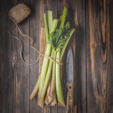 Sağlıklı bir diyet yemek tarifleri için yönetim kurulu malzemeler kesme tarihinde mutfak bıçağı ile taze genç ravent kaynaklanıyor organik gıda sebze ahşap arka plan, düşük anahtar kopyalama alanı üstten görünüm yumuşak odak üzerinde detoks