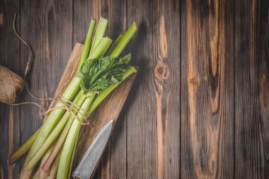 Sağlıklı bir diyet yemek tarifleri için yönetim kurulu malzemeler kesme tarihinde mutfak bıçağı ile taze genç ravent kaynaklanıyor organik gıda sebze ahşap arka plan, düşük anahtar kopyalama alanı üstten görünüm yumuşak odak üzerinde detoks