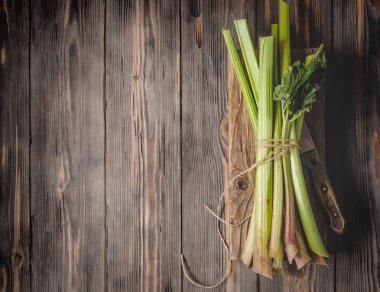 Sağlıklı bir diyet yemek tarifleri için yönetim kurulu malzemeler kesme tarihinde mutfak bıçağı ile taze genç ravent kaynaklanıyor organik gıda sebze ahşap arka plan, düşük anahtar kopyalama alanı üstten görünüm yumuşak odak üzerinde detoks