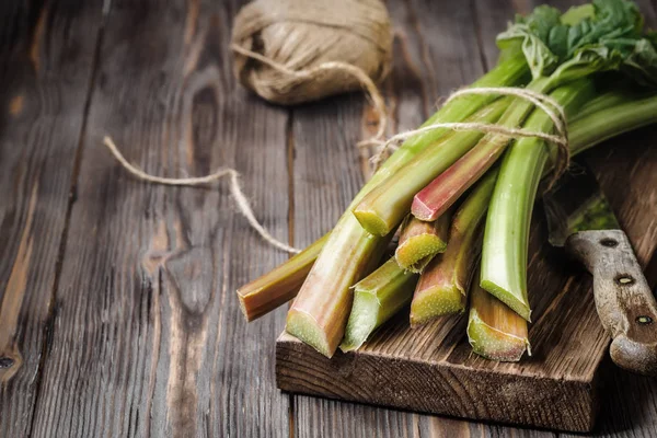 Sağlıklı bir diyet yemek tarifleri için yönetim kurulu malzemeler kesme tarihinde mutfak bıçağı ile taze genç ravent kaynaklanıyor organik gıda sebze ahşap arka plan, düşük anahtar kopyalama alanı üstten görünüm yumuşak odak üzerinde detoks