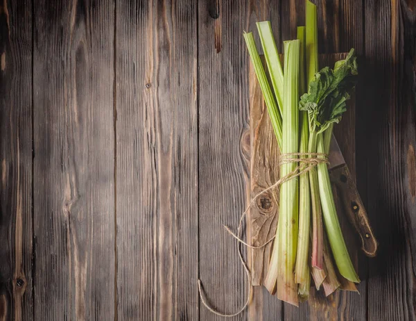 Sağlıklı bir diyet yemek tarifleri için yönetim kurulu malzemeler kesme tarihinde mutfak bıçağı ile taze genç ravent kaynaklanıyor organik gıda sebze ahşap arka plan, düşük anahtar kopyalama alanı üstten görünüm yumuşak odak üzerinde detoks