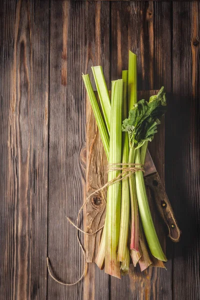 Sağlıklı bir diyet yemek tarifleri için yönetim kurulu malzemeler kesme tarihinde mutfak bıçağı ile taze genç ravent kaynaklanıyor organik gıda sebze ahşap arka plan, düşük anahtar kopyalama alanı üstten görünüm yumuşak odak üzerinde detoks