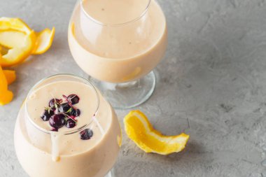 İki kokteyl cam ile smoothies milkshake sağlıklı içecek portakal narenciye peel muz süt yoğurt ve dondurma siyah frenk üzümü sağlıklı diyet yiyecek çilek ile