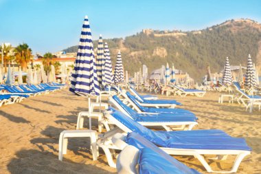 Gün batımında okyanus deniz kenarında kum plajındaki mavi minder ile boş şezlong