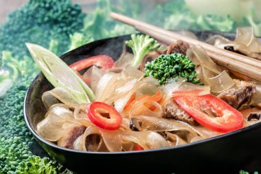 Tatlı ekşi soslu et sebze biber pırasa kase chopsticks taze brokoli arka plan üzerinde sıcak Asya baharatlı yemek kalın kesme cam erişte mung fungosa fasulye.